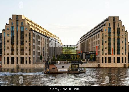 Office buildings  Cuvry Campus with Lieferando headquarter at the river Spree on which a boat is cruising near the Oberbaumbrücke in Berlin-Kreuzberg. Stock Photo