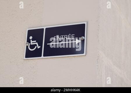 disabled accessible entree french text entry sign posting with wheelchair handicap logo with arrow pointing side Stock Photo