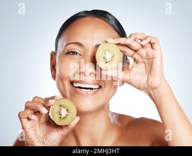 Beauty, skin and kiwi, portrait of woman with smile on face for vitamin c facial detox and happy on studio background. Healthy skincare, wellness and Stock Photo