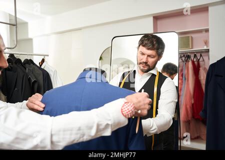 Professional fashion designers fitting item of clothing on mannequin Stock Photo