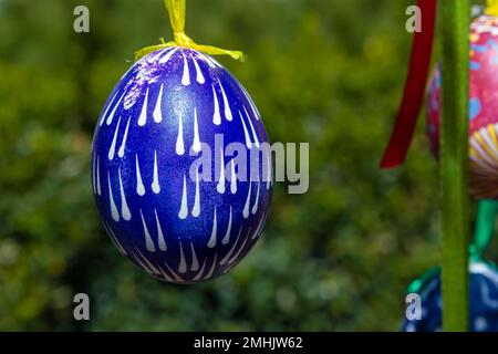 Painted eggs hang from the branches of the Easter tree. The focus is on a yellow egg painted by children by hand. High quality photo Stock Photo