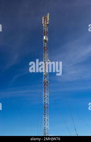 Telecommunication tower for mobile phone with antennas over a blue sky. Distribution function of contract mobile phones. Stock Photo