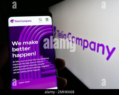 Person holding mobile phone with webpage of telecommunications company Telia Company AB on screen with logo. Focus on center of phone display. Stock Photo