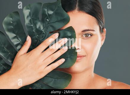 Palm leaf, face and woman in portrait with hand for beauty, manicure and natural cosmetics isolated on studio background. Eco friendly cosmetic care Stock Photo
