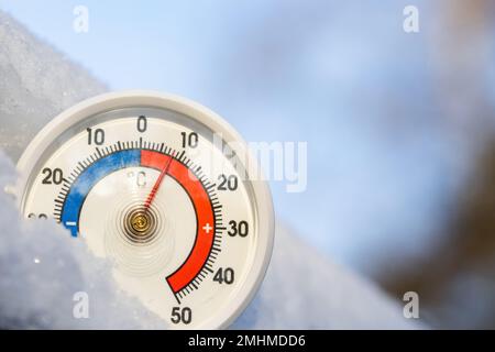 Thermometer with celsius scale in the snow showing plus 8 degree ambient temperature. Unusually high winter conditions. Warm winter weather and climat Stock Photo