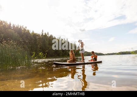 Kids paddleboarding on lake Stock Photo