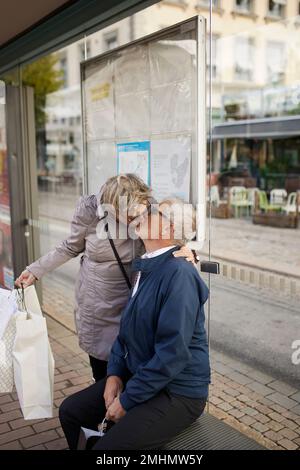 Mature couple kissing at bus stop Stock Photo