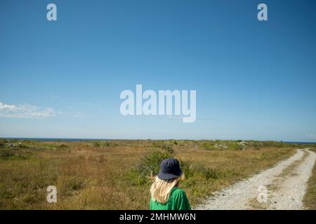 Blond girl on road leading to sea coast Stock Photo