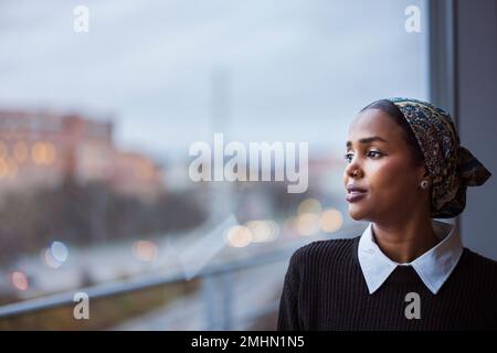 Young woman looking through window Stock Photo