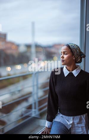 Young woman looking through window Stock Photo
