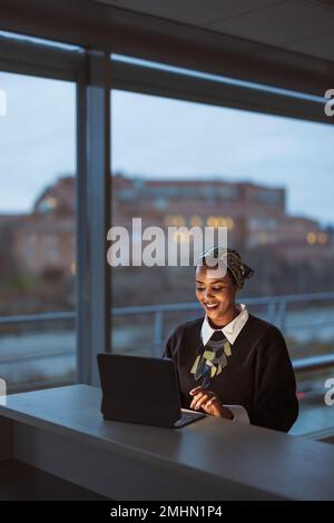 Smiling young woman working on laptop Stock Photo