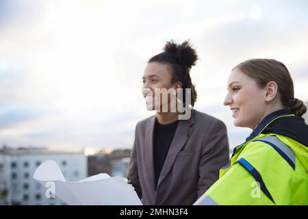 Architects talking while holding blueprints Stock Photo