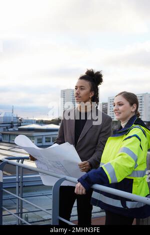 Architects talking while holding blueprints Stock Photo