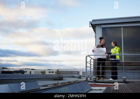 Architects talking while holding blueprints Stock Photo