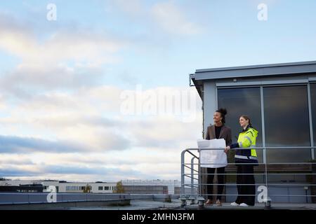 Architects talking while holding blueprints Stock Photo