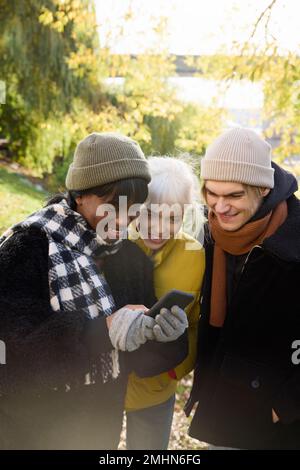 Smiling young friends looking at cell phone Stock Photo