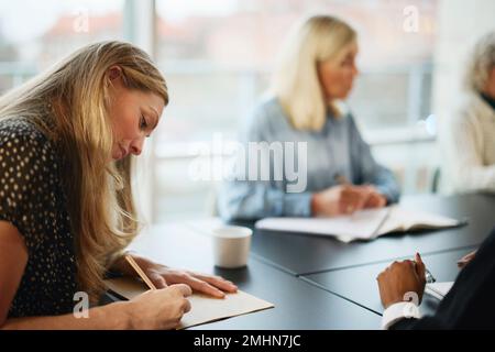 Woman taking notes during meeting Stock Photo
