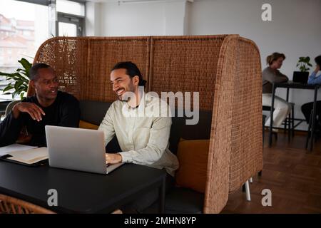 Men using laptop in cafeteria Stock Photo