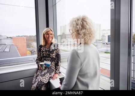 Businesswomen talking during coffee break in office Stock Photo