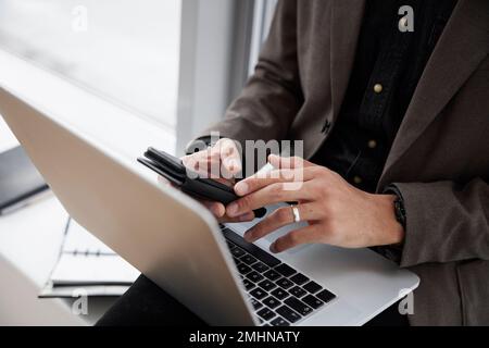Businessman using laptop and phone in office Stock Photo