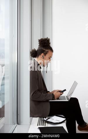 Young businessman using laptop and phone in office Stock Photo