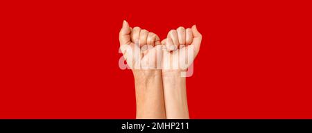 Girl power. Peoples raised fist air fighting on a red background. Competition, teamwork concept, space for text. Stock Photo