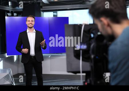 Presenter and video camera operator working in studio. News broadcasting Stock Photo