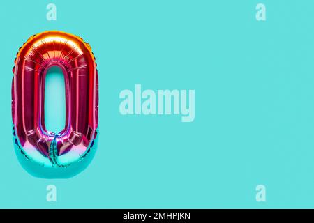 Rainbow foil balloon number, digit zero. Top view. Colored numeral on blue background. Stock Photo
