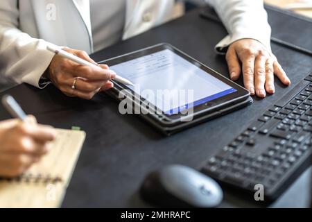 The hands of two female colleagues are using a digital tablet and a notebook. A business meeting to discuss financial management, accounting or financ Stock Photo