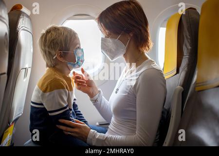 Mother and child, boy and mom, sitting in airplane, child playing on tablet, family trip Stock Photo