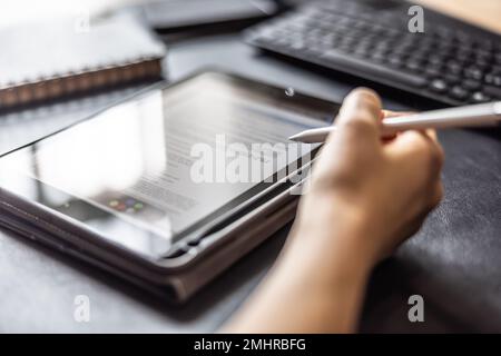 Woman working with digital tablet and pen, checking document, contract or agreement - Close up. Stock Photo