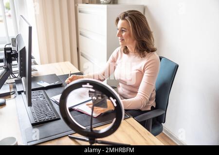 Accountant working with a desktop computer at office. A businesswoman gives an online interview with her client. Stock Photo
