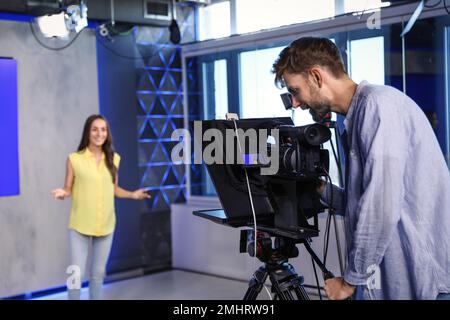 Professional video camera operator and presenter working in studio Stock Photo