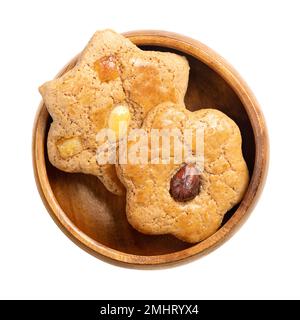 Homemade gingerbread cookies, in a wooden bowl. Sweet, brown, flat and star-shaped baked goods, with candied fruits, and with nut halves on top. Stock Photo