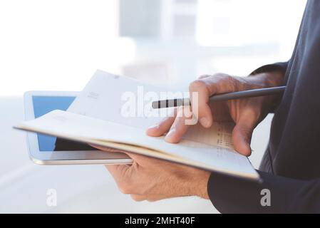 Closeup of young businessman planning with notebook and tablet in his hands Stock Photo
