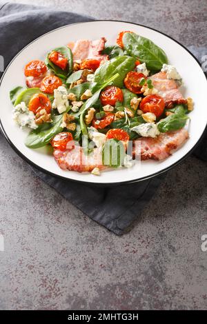 Salad with bacon, spinach, roquefort cheese, walnuts, tomatoes, basil and garlic close-up in a plate on the table. Vertical Stock Photo