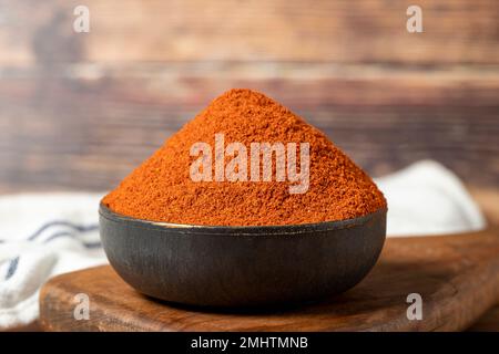 Red chili powder spice. Ground sweet paprika spice in bowl on wood background. Dry spice concept. close up Stock Photo