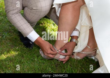 man groom footwear is putting on woman bride marriage shoes for the wedding day Stock Photo