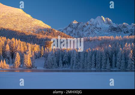 A winter's morning at Strbske Pleso, with the High Tatras standing tall and the lake reflecting the sun's first rays. Stock Photo