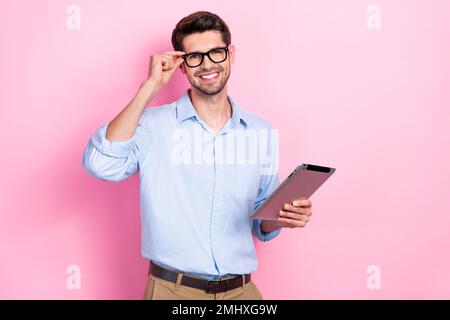 Photo of young entrepreneur businessman wear office blue shirt touch new specs smiling hold notepad for agent job isolated on pink color background Stock Photo