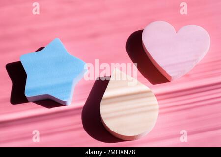 Cosmetic sponges in pastel colors on a pink background with deep shadows. Beauty concept. Copy space Stock Photo