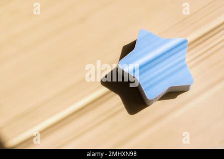 Blue cosmetic sponge in the shape of a star on a beige background with deep shadows. Beauty concept. Copy space Stock Photo