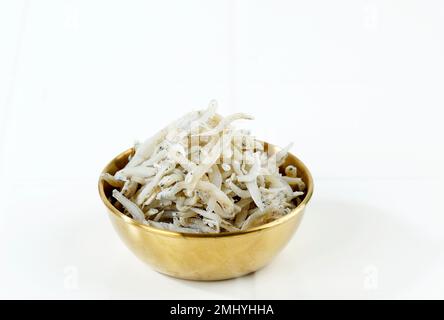 Fresh Dried Anchovies on White Background. Raw Dry Salted Sea Fish. Saltwaterforage Fish. Ikan Asin Teri Medan. Copy Space Stock Photo