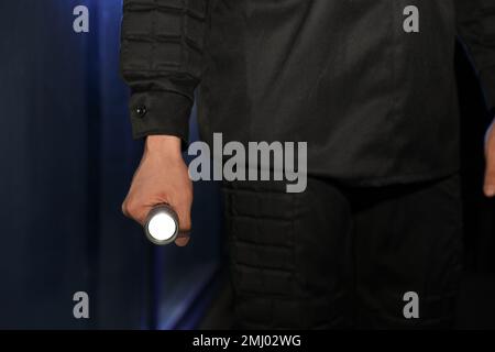 Male security guard with flashlight in dark room, closeup Stock Photo