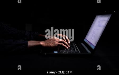 Hands typing out on laptop in dark room Stock Photo