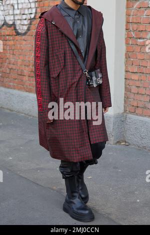 MILAN, ITALY - JANUARY 14, 2023: Man with black and red checkered coat and gray shirt before Fendi fashion show, Milan Fashion Week street style Stock Photo