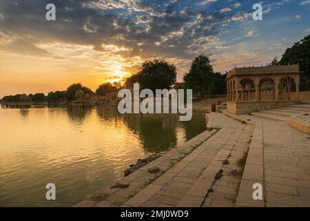 Beautiful sunset at Gadisar lake, Jaisalmer, Rajasthan, India. Setting sun and colorful clouds in the sky with view of the Gadisar lake. Stock Photo