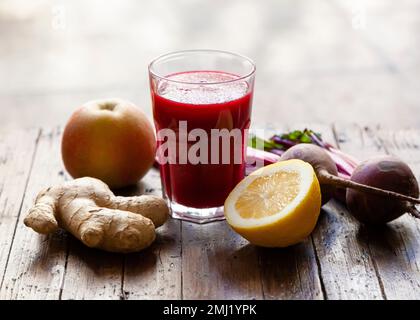 Natural antioxidant drink of beetroot, ginger, apple and lemon on a rustic, wooden table. Stock Photo