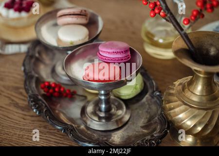 Multi-colored macaroons on an old silver dish, on the table. Stock Photo