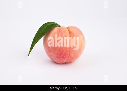 One fresh peach on a white background. Close-up from the front. Stock Photo